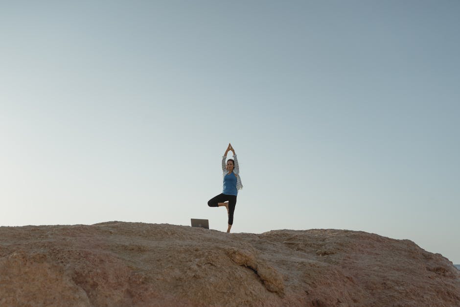 A person in a meditative yoga pose against a scenic sunrise